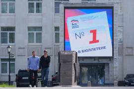 Unas personas pasan frente a una valla publicitaria digital en Moscú, el lunes 14 de septiembre de 2026, que promociona al partido Rusia Unida de cara a las elecciones parlamentarias.