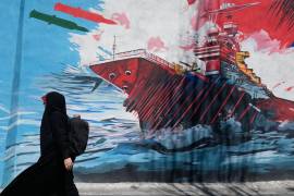 Una mujer pasa junto a un mural que muestra un portaaviones estadounidense bajo ataque en el centro de Teherán, Irán, el lunes 8 de junio de 2026.