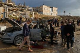 Varios palestinos observan un auto destruido tras un ataque israelí en la Ciudad de Gaza; en esta agresión se reportó la muerte del número 2 de Hamás.