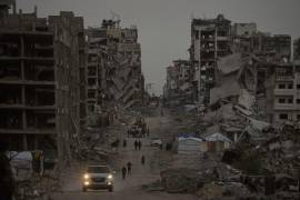 Palestinos caminan entre la destrucción en el barrio de Al-Karama, en la ciudad de Gaza.