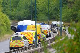 Policías laboran en el lugar donde se registró un choque mortal en que se vieron implicados un vehículo policial y un auto en Inglaterra.