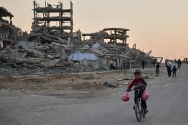 Un niño monta en bicicleta por una calle dañada en el campamento de Al-Shati en la ciudad de Gaza.