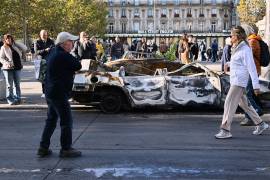 Gente mira a un auto calcinado en Place de la Republique el día después de una manifestación contra el creciente coste de la vida, que se suma a las protestas estudiantiles, en París.
