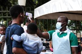 Un funcionario de salud utiliza un termómetro para examinar a las personas frente al Hospital Musulmán de Kibuli en Kampala, Uganda, el sábado 16 de mayo de 2026.
