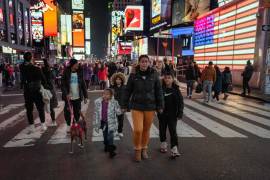 Henry Aguilar y Leivy Ortega con sus hijos, quienes miran asombrados las pantallas iluminadas y los superhéroes disfrazados en Times Square en Nueva York.