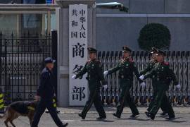 Soldados paramilitares y un policía con un perro rastreador pasan ante la puerta del Ministerio chino de Comercio, en Beijing, el 3 de abril de 2025.