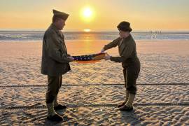 Christophe Receveur y su hija Julie, de Francia, extienden una bandera estadounidense que él compró hace seis meses en Gettysburg, Pensilvania, para conmemorar el Día D en la playa Utah, Normandía.