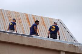 Agentes del orden inspeccionan el tejado de un edificio de apartamentos cerca de la escena de un tiroteo en una oficina del CE en Dallas, en el que un migrante mexicano resultó herido.