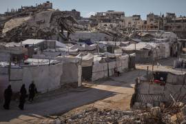 Palestinos caminan por una calle flanqueada por tiendas de campaña que albergan a personas desplazadas por los ataques militares israelíes en la guerra entre Israel y Hamás, en la ciudad de Gaza.