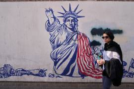 Una mujer pasa junto a un mural antiestadounidense en la pared de la antigua embajada de Estados Unidos, ahora convertida en museo, el viernes 12 de junio de 2026, en Teherán, Irán.