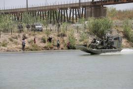 Un grupo de migrantes tratando de cruzar la alambrada instalada por la Guardia Nacional de Texas.
