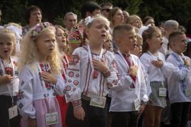 Alumnos cantan el himno nacional de Ucrania en la ceremonia de regreso a clases en Bucha.