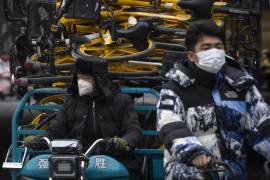 Personas con máscaras faciales esperan en una intersección en el distrito comercial central de Beijing.