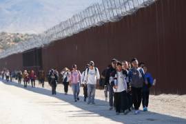 Un grupo de personas, incluidos muchos de China, camina junto al muro tras cruzar la frontera con México para pedir asilo, el 24 de octubre de 2023, cerca de Jacumba, California.