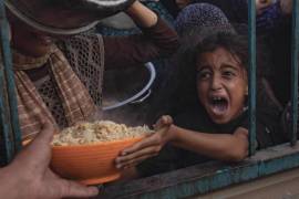Niños desplazados palestinos se agolpan para recoger alimentos donados en el campamento de Khan Yunis, sur de la Franja de Gaza.