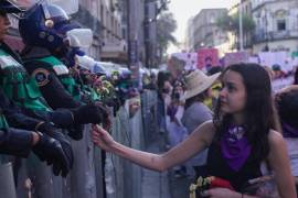 Una mujer entrega flores a la policía antidisturbios durante una marcha contra la violencia de género con motivo del Día Internacional de la Mujer, en CDMX.