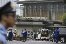 Agentes de policía trabajan cerca de un vehículo (centro) que fue estrellado contra una barricada cerca de la oficina del primer ministro (detrás), en Tokio.