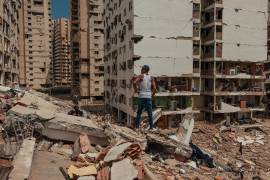 Un hombre observa las viviendas expuestas de edificios enteros que colapsaron completamente, mientras se teme que la crisis política y económica agrave la recuperación.