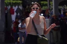 Una mujer bebé agua para mitigar el calor en el Zócalo capitalino. Se presentará una ola de calor en la capital hasta el próximo jueves.