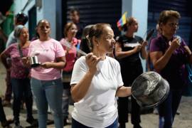 Varias personas golpean cacerolas durante una protesta contra los cortes de electricidad en San Mateo, Venezuela.