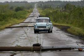 La gente conduce por una carretera llena de cables eléctricos caídos después del paso del huracán Rafael en San Antonio de los Baños, Cuba.