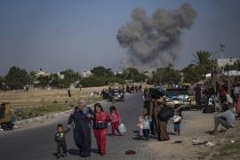 Palestinos huyen el sábado de este a oeste de Khan Younis, en la Franja de Gaza, mientras al fondo se observa una enorme fumarola causada por los bombardeos israelíes.