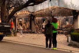 Personas observan una casa afectada por un incendio en Altadena, California. Con más de 100 mil personas evacuadas, se estima que los incendios en Los Ángeles provocaría pérdidas de más de 50 mil mdd.