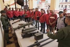 Un miembro de la guardia presidencial muestra armas a las personas que se inscribieron para unirse a la milicia civil durante una campaña de reclutamiento nacional organizada por el gobierno de Nicolás Maduro