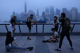 Vecinos con mascarillas hacen ejercicio en el paseo marítimo al amanecer del miércoles 1 de junio de 2022 en Shanghái.