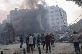 Reporteros observan mientras palestinos inspeccionan un edificio alcanzado por un bombardeo israelí en la Ciudad de Gaza, 8 de octubre de 2023.