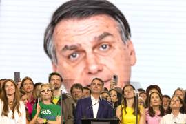 El senador Flávio Bolsonaro (c) reacciona durante la transmisión de un video de su padre, el expresidente Jair Bolsonaro enviando un mensaje de apoyo, en la convención nacional del Partido Liberal (PL).