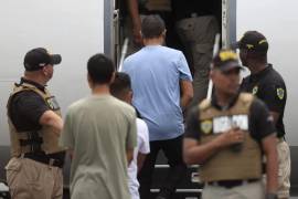 Fotografía de archivo de personas subiendo a un avión mientras son custodiadas por integrantes del Servicio Nacional de Migración de Panamá.