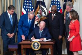 El presidente de los Estados Unidos, Joe Biden, rodeado de legisladores demócratas, firma la Ley de Reducción de la Inflación en el Comedor Estatal de la Casa Blanca en Washington, DC.