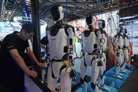 Un trabajador junto a una fila de robots humanoides en la conferencia World AI Conference en Shanghái, el viernes 17 de julio de 17, 2026.