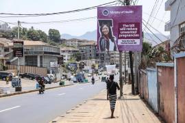 Una mujer pasa junto a un cartel que promociona el proyecto de ley de Maternidad Segura, en Wilkinson Road, Freetown, Sierra Leone, el 12 de marzo de 2025.