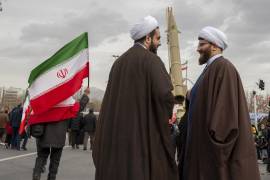 Dos clérigos hablan entre sí cerca de un misil en exhibición para conmemorar el 47º aniversario de la Revolución Islámica en Teherán.