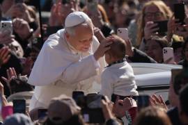 El papa León XIV acaricia a un bebé a su llegada a la Plaza de San Pedro, en el Vaticano, para su audiencia general semanal.