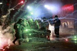 Manifestantes usan fuegos artificiales contra la policía mientras ésta bloquea una calle para evitar que marchen contra la decisión del gobierno de suspender por cuatro años las negociaciones para unirse a la Unión Europea, fuera de la sede del Parlamento en Tiflis. FOTO: Ap.