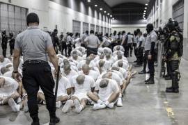 En esta fotografía proporcionada por la oficina de prensa de la presidencia de El Salvador, guardias penitenciarios trasladan a presuntos pandilleros venezolanos, deportados de Estados Unidos, al Centro de Confinamiento del Terrorismo (CECOT), en Tecoluca, El Salvador. FOTO: