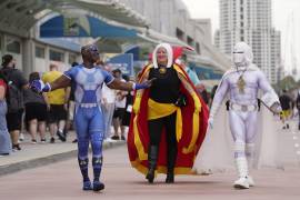 Personas disfrazadas como superhéroes caminan afuera de la noche previa a la Comic-Con de the San Diego.