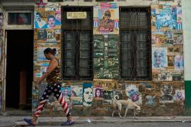Una mujer pasa junto a un edificio en el que se exhiben fotografías del expresidente cubano Raúl Castro y del expresidente venezolano Nicolás Maduro, en La Habana, Cuba.