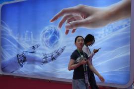 Visitantes caminan junto a un cartel con una mano humana y una robótica en la Expo Internacional China de Cadena de Suministro en Beijing, el lunes 22 de junio de 2026.