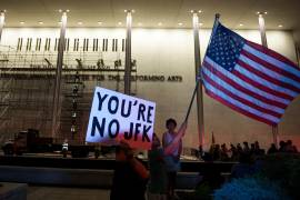 Manifestantes ondean una bandera de Estados Unidos y carteles mientras operarios se preparan para retirar el nombre del presidente Donald Trump del John F. Kennedy Center for the Performing Arts en Washington, el 13 de junio de 2026.
