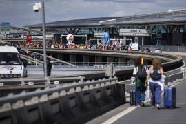 Viajeros arriban a pie al aeropuerto Charles de Gaulle, al norte de Paris, mientras trabajadores en huelga protestan el 1 de julio del 2022. (AP Foto/ Thomas Padilla)