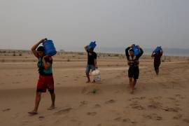 Personas llevan agua desde Humaita hacia la comunidad de Paraizinho, a lo largo de un tramo seco del río Madeira, un afluente del Amazonas, en medio de una sequía, el 8 de septiembre de 2024, en Brasil.