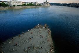 Personas caminan por un banco de arena bajo el puente Margarita del río Danubio, en el centro de Budapest, Hungría, mientras el río, que atraviesa diez países europeos, ha descendido a niveles de caudal nunca vistos.