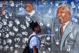 Una estudiante camina frente a un mural de Nelson Mandela en Johannesburgo, Sudáfrica.
