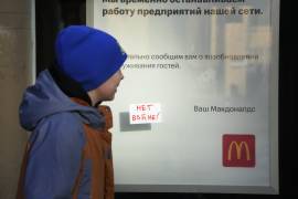 Un niño ve un letrero que dice: ‘¡No a la guerra!’ pegado a una ventana del restaurante McDonald’s con un aviso de cierre en San Petersburgo, Rusia, el martes 15 de marzo de 2022.