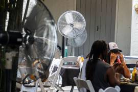 Dos personas se colocan alrededor del patio del Club Bourbon Heat durante una ola de calor récord en el Barrio Francés de Nueva Orleans.