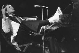 Jerry Lee Lewis apoya su pie en el piano mientras se recuesta y agradece los aplausos de los fanáticos durante el Rock ‘n’ Roll Revival anual en el Madison Square Garden de Nueva York el 14 de marzo de 1975.